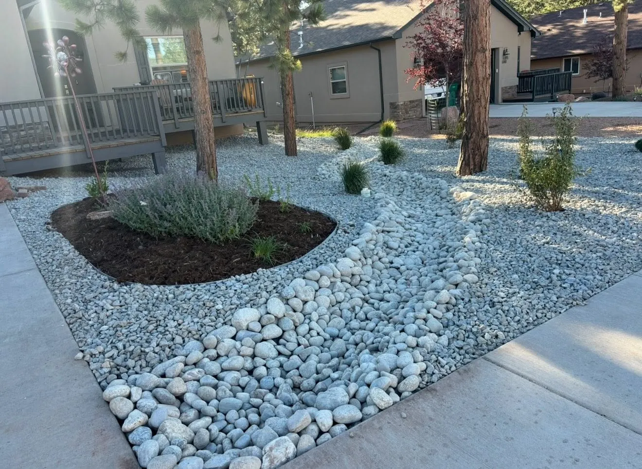 Landscape bed of river stones and shrubs beside a driveway