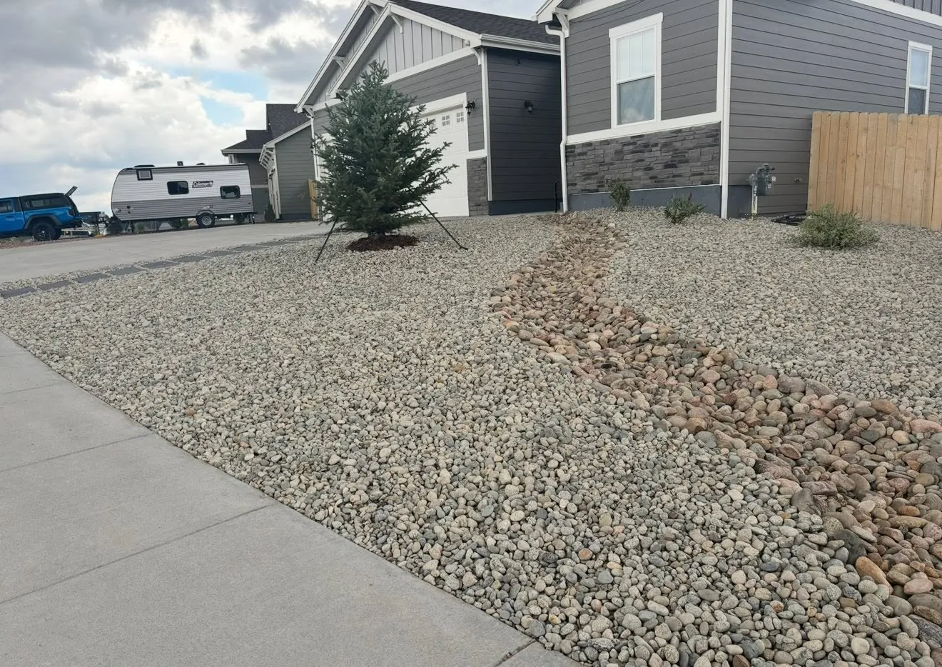 Gravel front yard with a dry creek bed of larger rock along the sidewalk