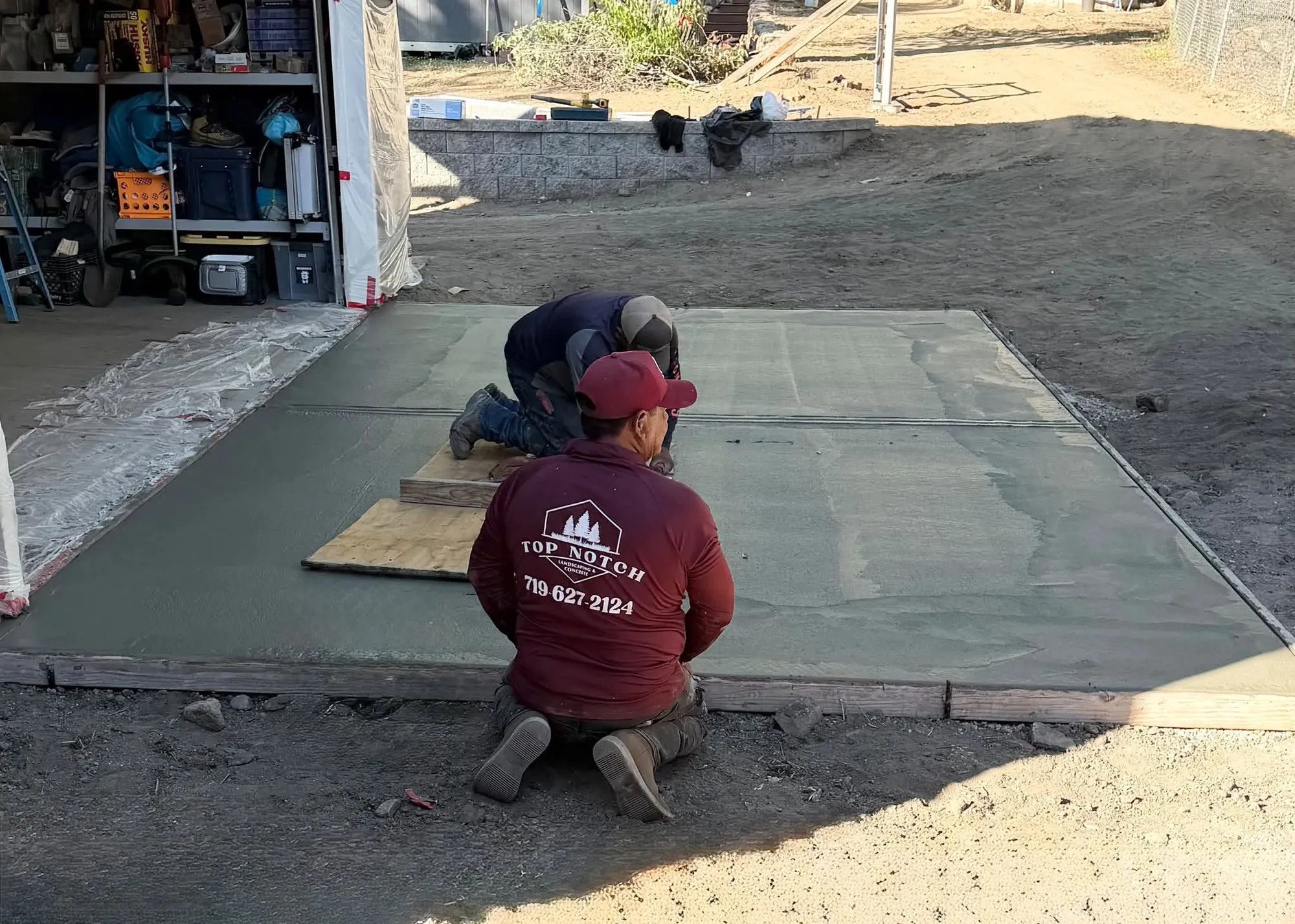 Crew member smoothing a freshly poured concrete slab